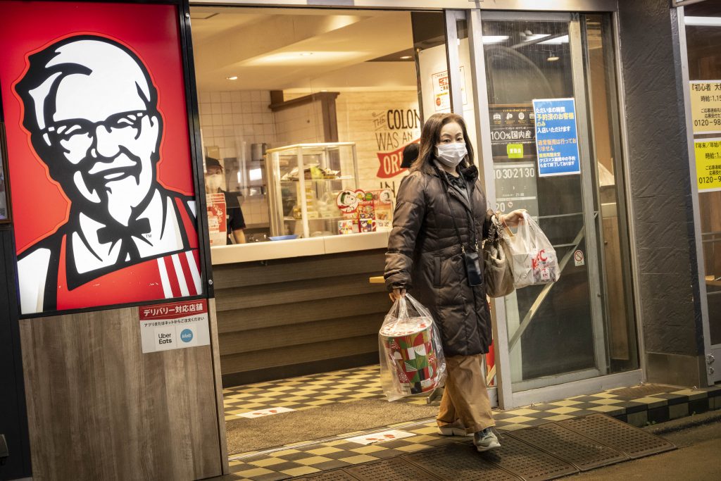 Egy nő karácsonyi kosarakkal a kezében távozik egy KFC étteremből Tokióban karácsony este, 2022. december 24-én (Fotó: Yuichi Yamazaki/AFP)