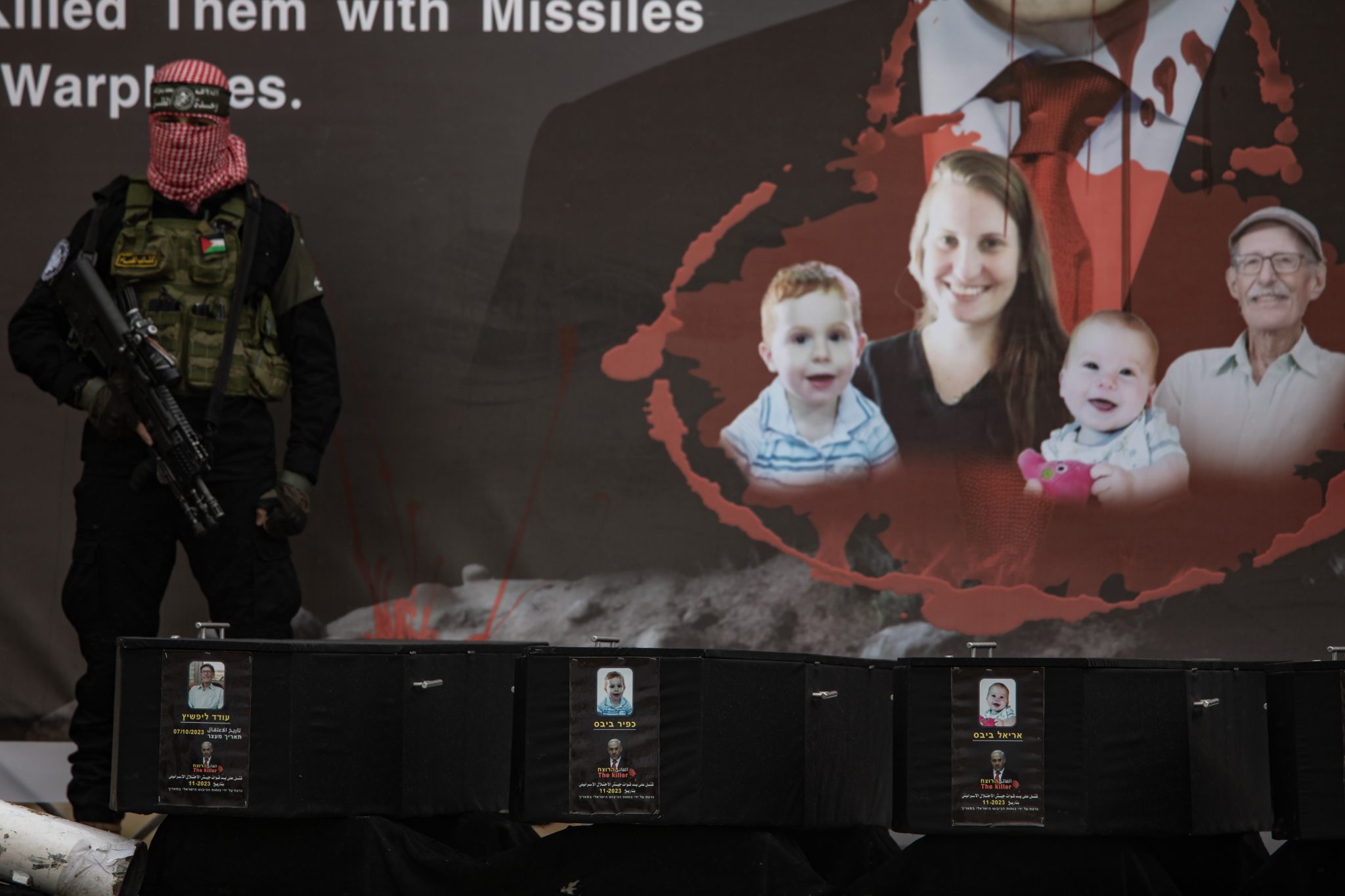 A Hamász palesztin terrorszervezet maszkot viselő fegyverese áll az izraeli túszok koporsója mellett, mielőtt a holttesteket átadnák a Nemzetközi Vöröskereszt képviselőinek 2025. február 20-án. A Bibasz család tragédiája az egyik legmegrázóbb példája annak, hogyan próbálta a Hamász tudatosan manipulálni a közvéleményt az október 7-i támadást követően. A Hamász a zsidó államot hibáztatva azt állította, hogy a 9 hónapos Kfirt, a 4 éves Arielt és édesanyjukat egy izraeli légicsapás ölte meg. A vizsgálatok később megállapították, hogy a gyermekeket puszta kézzel ölték meg a palesztin fegyveresek (Fotó: MTI/EPA/Haiszam Imad)
