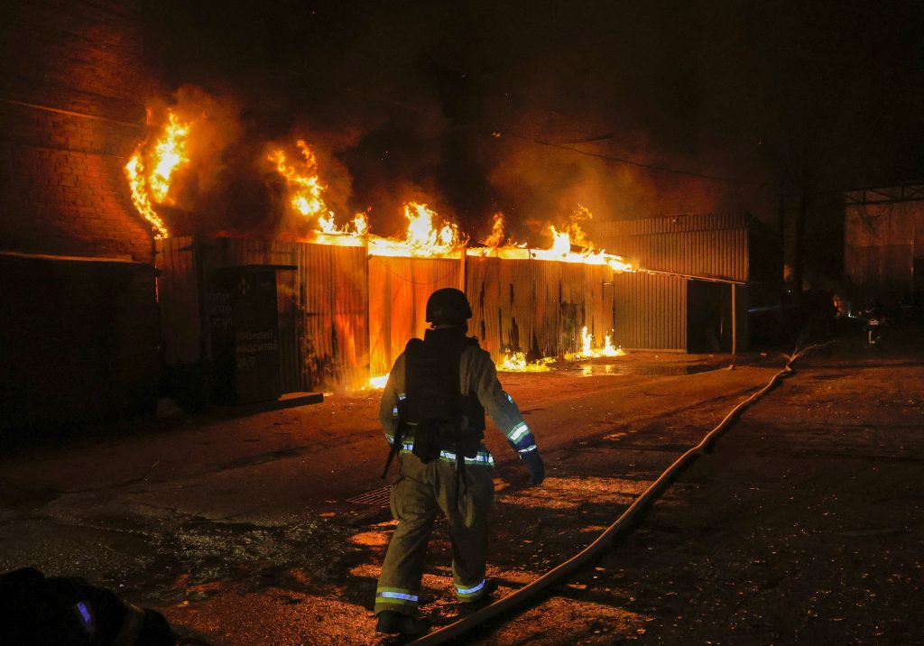 Tűzoltók dolgoznak egy lángoló épületnél, amelybe orosz drón csapódott a kelet-ukrajnai Harkivi területen (Fotó: MTI/EPA/Szergej Kozlov)