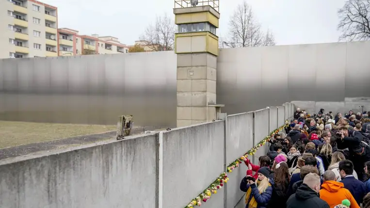 Emberek virágokat helyeznek el az egykori berlini fal megmaradt részénél a fal ledöntésének 35. évfordulója alkalmából rendezett megemlékezésen. (Fotó: MTI/AP/Ebrahim Noruzi)