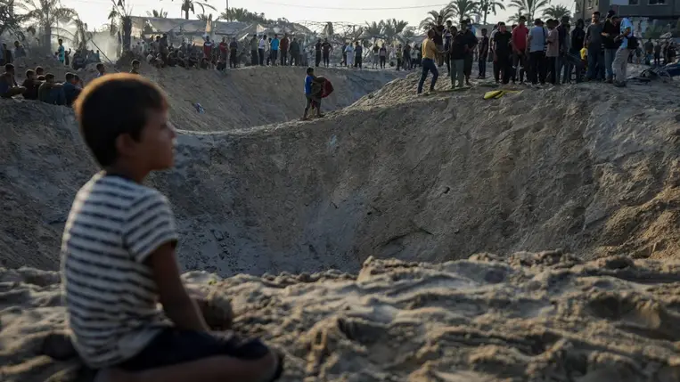 Bombatölcsérek mellett palesztin emberek a Gázai övezet déli részén, Hán-Júnisz mellett fekvõ Muvasziban, egy humanitárius övezetben 2024. szeptember 10-én, miután Izrael légicsapás érte palesztin menekültek sátortáborát. (Fotó: MTI/AP)