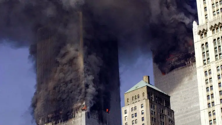 Sűrű füsttel lángolnak a New York-i Világkereskedelmi Központ ikertornyai 2001. szeptember 11-én (Fotó: MTI/EPA/AFP/Stan Honda)