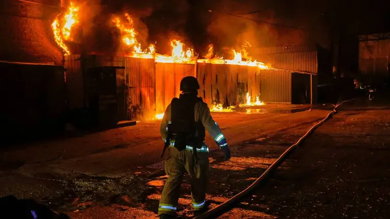 Tűzoltók dolgoznak egy lángoló épületnél, amelybe orosz drón csapódott a kelet-ukrajnai területen (Fotó: MTI/EPA/Szergej Kozlov)