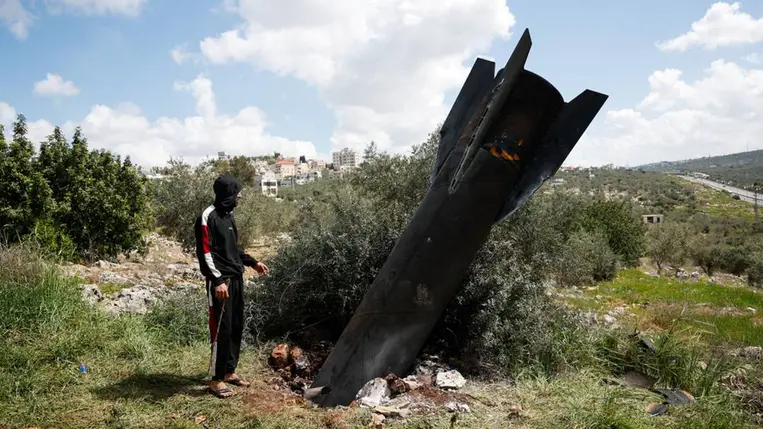 Egy személy áll a földbe szorulva talált rakétamaradványok mellett Kifl Haris faluban, Nablus közelében 2026. március 24-én. Fotó: Mohamad Torokman / Reuters