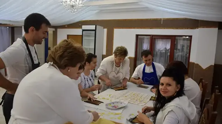 Homoki Szilvia, aki a falusi vendéglátással szülőfalujában, Beregdédában már két évtizeddel ezelőtt kezdett foglalkozni, ezúttal a csörögének való tésztát gyúrja be, miközben a tanfolyam hallgatói körbe állják.