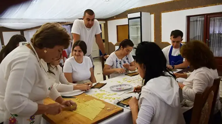 Homoki Szilvia, aki a falusi vendéglátással szülőfalujában, Beregdédában már két évtizeddel ezelőtt kezdett foglalkozni, ezúttal a csörögének való tésztát gyúrja be, miközben a tanfolyam hallgatói körbe állják.