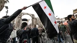 A szíriai ellenzék zászlóját tartja egy férfi a Hamidija-piac bejáratánál Damaszkusz óvárosában, 2024. december 10-én (Fotó: Louai BESHARA/AFP)