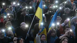 A résztvevők okostelefonjaik fényeit és egy ukrán zászlót mutatnak be a nevezetes berlini Brandenburgi kapu előtt 2025. március 9-én, az Ukrajna melletti tüntetésen / Fotó: AFP