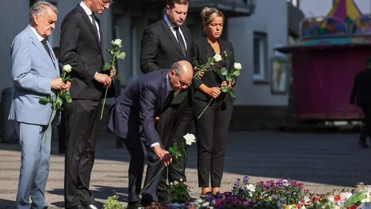 Olaf Scholz német kancellár, Tim Kurzbach solingeni polgármester és Mona Neubaur, Észak-Rajna-Vesztfália gazdasági és energiaügyi minisztere virágot helyez el a városban elkövetett solingeni késes támadás helyszínének közelében 2024. augusztus 26-án Fotó: MTI/EPA pool/Christopher Neundorf