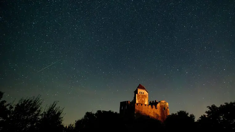 A hosszú expozíciós idõvel készült képen csíkot húz az égen egy hullócsillag a hollókõi vár felett 2023. augusztus 13-án, a Perseida meteorraj hullásának idején. (Fotó: MTI/Komka Péter)