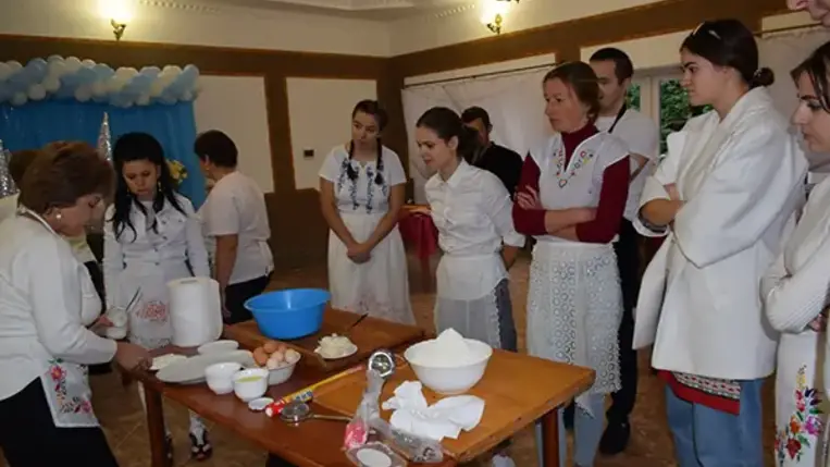 Homoki Szilvia, aki a falusi vendéglátással szülőfalujában, Beregdédában már két évtizeddel ezelőtt kezdett foglalkozni, ezúttal a csörögének való tésztát gyúrja be, miközben a tanfolyam hallgatói körbe állják.